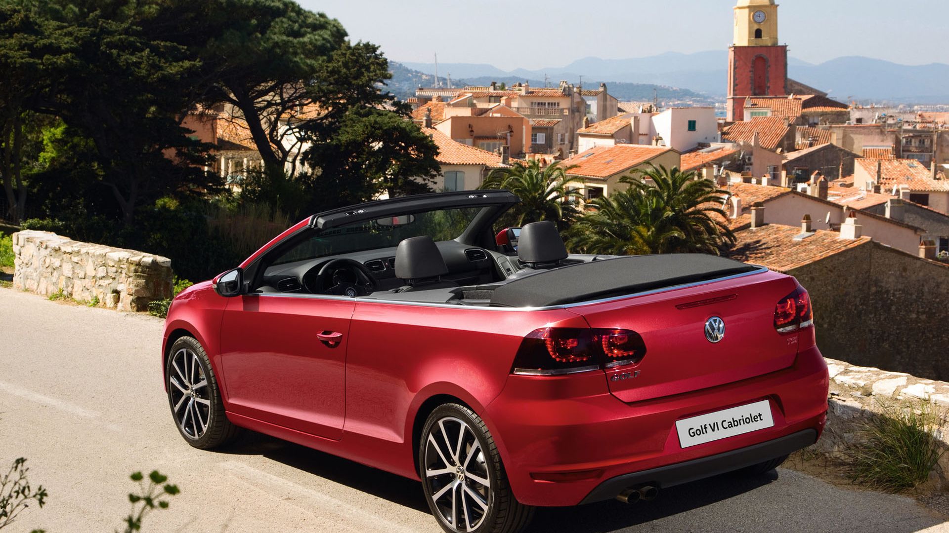 Das VW Golf 6 Cabrio in rot von hinten, im Hintergrund eine Stadt