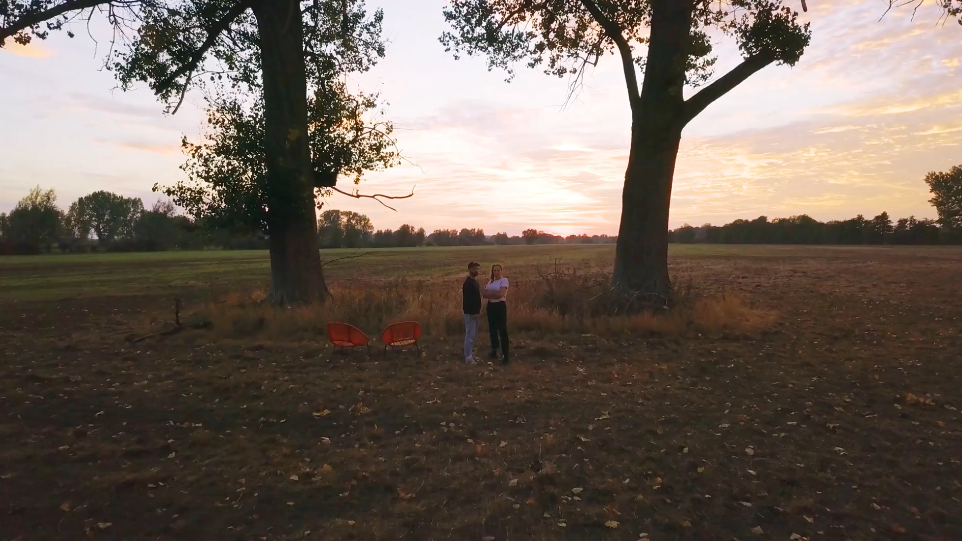 Marcus und Anna stehen auf dem Feld und schauen in die Ferne.