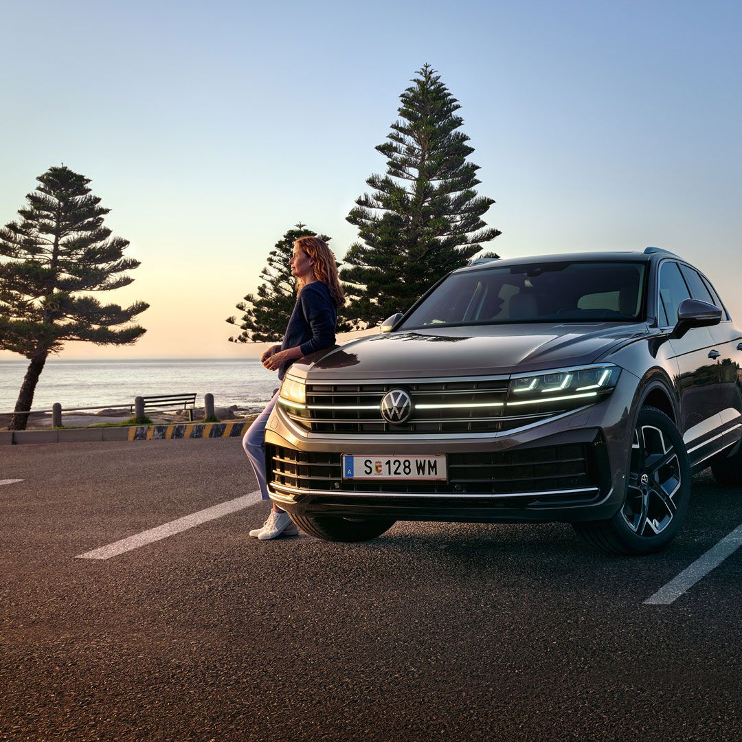 VW Touareg Elegance za súmraku pri mori so zapnutými svetlometmi HD Matrix. 